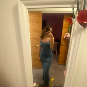 Blå långklänning - Snygg blå långklänning med en tight passform och axelbandslös design. Perfekt för en elegant kvällslook. Klänningen har en stilren och enkel stil som framhäver figuren.