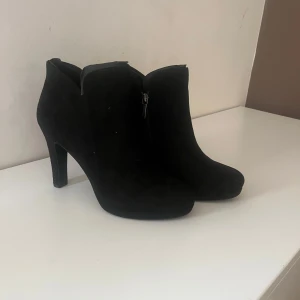 Svarta stövletter med klack från Tamaris.  - Snygga svarta stövletter i mocka med dragkedja på sidan. Oanvända. Hund finns i hemmet. 