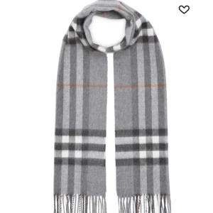 Grå rutig halsduk burberry - Snygg grå halsduk med klassiskt rutigt mönster i vitt och beige. Perfekt för att hålla sig varm under kyliga dagar. Den har fransar i ändarna som ger en extra touch av stil.