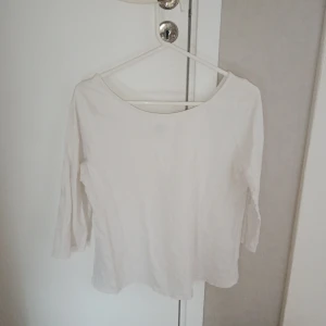 Basic Vit långärmad topp - Säljer en enkel och stilren vit långärmad topp. Perfekt för en minimalistisk look. Toppen har en rund hals och är tillverkad i ett mjukt material.
