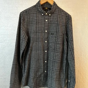 Rutig skjorta från Lee - Snygg rutig skjorta från Lee i svart och vit. Skjortan har långa ärmar och knappar framtill samt på ärmsluten. Perfekt för en stilren look.