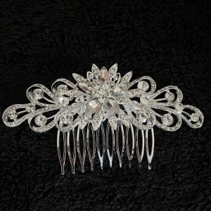 Silverfärgad hårkam med blommönster - Elegant silverfärgad hårkam med ett intrikat blommönster och glittrande detaljer. Perfekt för att ge en extra touch av glamour till din frisyr.