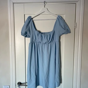 Ljusblå klänning  - Söt ljusblå klänning från Shein med puffiga kortärmar och smockdetaljer på ryggen. Perfekt för en somrig look. Söt passform