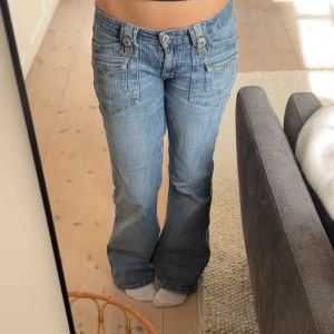 low waist bootcut jeans  - Snygga blå jeans från X-Mail med unika detaljer som dubbla knappar och bälteshällor framtill. Byxorna har en bootcut-stil och är perfekta för en avslappnad look. De har också praktiska fickor både fram och bak.