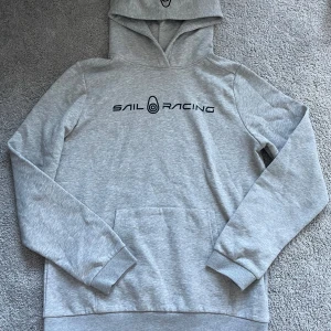 Grå hoodie från Sail Racing - Säljer en stilren grå hoodie från Sail Racing. Tröjan har inte någon fläck eller skada den är i topp skick och har inte används så mycket  pris är som alltid förhandlingsbart!!