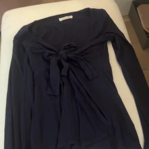 Långärmad topp med knyt  - Snygg marinblå långärmad topp med knyt framtill från design by si. Den är använd men inga tecken på defekter/ hör av vid intresse!