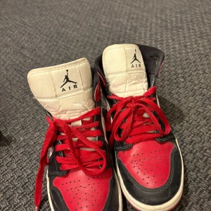 Nike Air Jordans i rött och svart - Snygga Nike Air Jordans i klassisk röd och svart färgkombination. Skorna har en hög design med snörning och den ikoniska Air-loggan på plösen. Perfekta för dig som vill ha en stilren och sportig look.