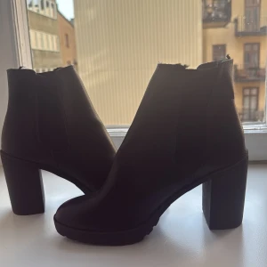 Svarta boots med klack  - Snygga svarta boots med hög klack och elastiska paneler på sidorna för enkel på- och avtagning. Skönt material på insidan (se bild).  Perfekta för att ge lite extra höjd och stil till din outfit.