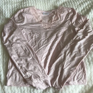Rosa långärmad topp från Gina Tricot - Säljer en söt rosa långärmad topp från Gina Tricot med spetsdetaljer vid v-ringningen. Perfekt för en romantisk look. 💖