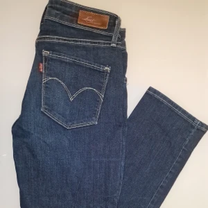 Levi's Demi Curve Classic Jeans - Snygga Levi's Demi Curve Classic jeans i mörkblå denim. Dessa jeans har en slim fit och är perfekta för en stilren look.