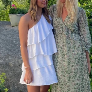 Vit axelbandslös klänning - Säljer en studentklänningar men också en klänning som är perfekt för sommaren. Söt vit axelbandslös klänning med volanger och one shoulder. Superskön och bekväm!! Nypris 1000kr