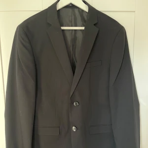 Svart premium kostym från Jack & Jones - Säljer en stilren svart premium kostym från Jack & Jones. Kostymen har passformen slim och är endast använd en gång under en skolavslutning. Säljer då den inte längre passar mig.