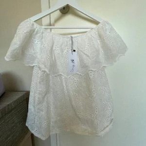 Vit offshoulder blus med spetsdetaljer - Säljer en söt vit offshoulder blus från Zara med vackra spetsdetaljer. Perfekt för sommarens alla tillfällen. Blusen har en luftig passform och volangdetaljer som ger en romantisk känsla. 🌸