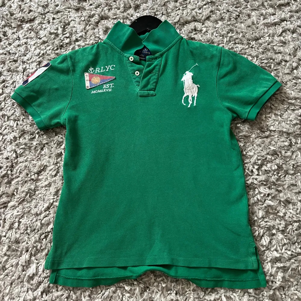 Säljer en grön pikétröja från Ralph Lauren med korta ärmar och klassisk krage. Tröjan har en stor vit logotyp på bröstet och broderade detaljer på ärmen. Perfekt för en avslappnad stil. Pris kan diskuteras och hör av er vid minsta fråga 🙌. Muu.