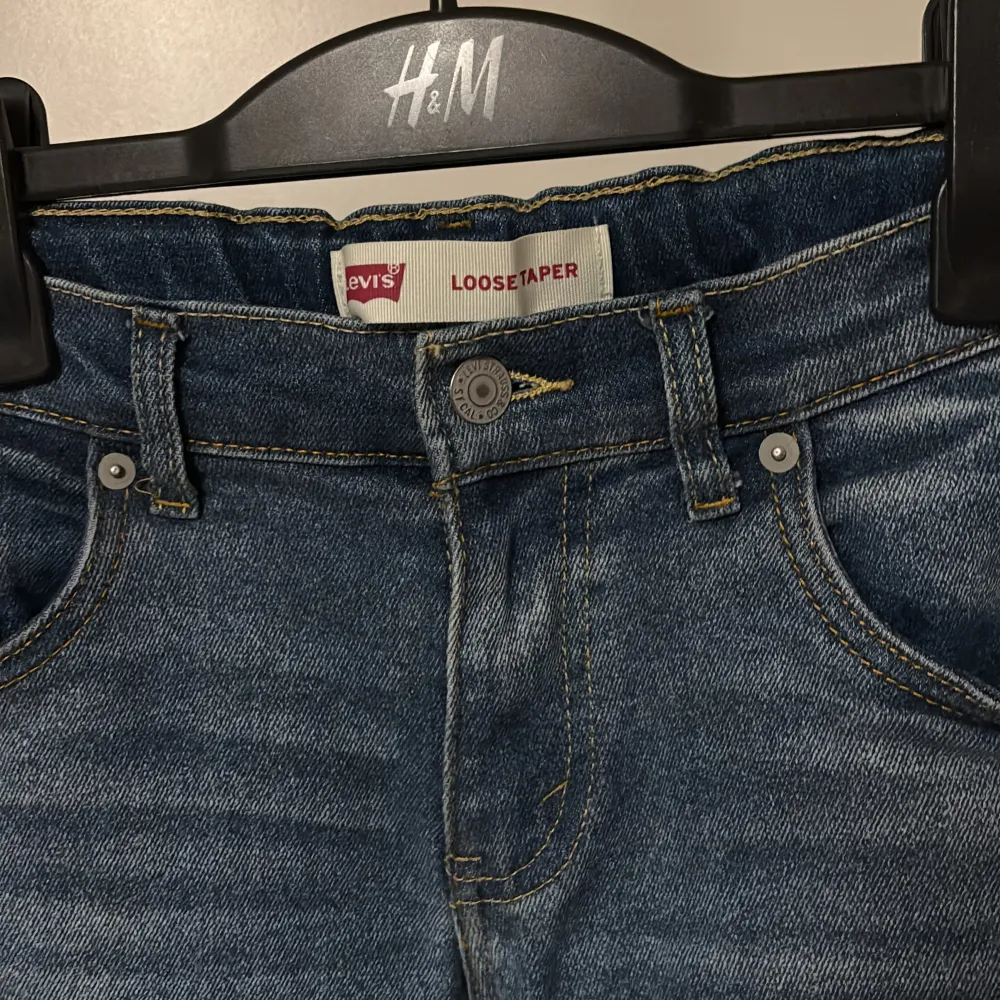 Snygga blå jeans från Levi's med en loose tapered passform. Klassisk femficksdesign och knappgylf. Perfekta för en avslappnad stil.. Farkut & Housut.