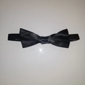 Svart fluga - Elegant svart fluga med en klassisk design. Perfekt för formella tillfällen och ger en stilren touch till din outfit. Enkel att justera för bästa passform.