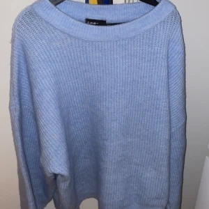 Ljusblå stickad tröja från Firefly - Mysig ljusblå stickad tröja från Firefly. Perfekt för kyliga dagar med sin mjuka och bekväma passform. Tröjan har långa ärmar och en bred ribbad kant vid halsen för extra stil. Ett måste i garderoben för en avslappnad look. Frakt tillkommer.