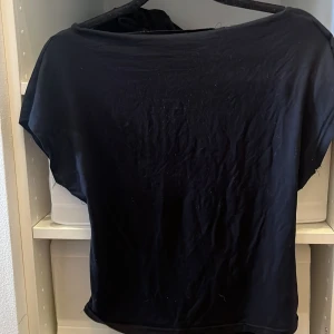 Svart topp med öppen rygg från SHEIN - Svart topp från SHEIN i storlek L med korta ärmar och en snygg öppen rygg. Tunt och mjukt material som känns skönt mot huden. Perfekt för dig som gillar en enkel men ändå cool look.