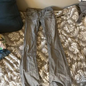 Grå jeansbyxor från Gina Tricot - Snygga grå utsvängda jeans  från Gina Tricot med vita kontrastsömmar och detaljerade bakfickor med knappar. Strl 164. Original pris 400💓💓