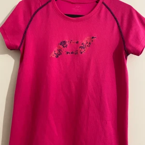 Rosa tränings-tshirt från SOC - Sportig rosa t-shirt från SOC med korta ärmar och rund hals. Materialet är lätt och andas, perfekt för träning. Snygga kontrastsömmar och diskret logga framtill. Passformen är normal och modellen är enkel men modern.