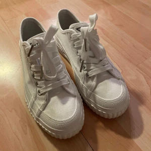 Aimn vita sneakers med platåsula strl 36/37 - Fräscha vita sneakers från Aimn med grov platåsula och klassisk snörning. Skorna är i canvas med silvriga metalldetaljer vid snörhålen och har en rund tå. Perfekta för dig som gillar en clean och stilren look med lite extra höjd. Storlek 36 men innermåttet är 24.0 cm så upplever de mer som storlek 37. Nyskick! Endast testade utomhus. 