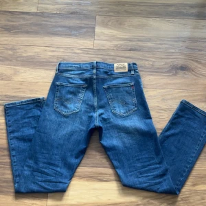 Blå Replay jeans straight fit - Snygga blå jeans från Replay med klassisk femficksmodell och raka ben. Jeansen har tydliga kontrastsömmar, Replay-logga på bakfickan och patch i läder bak i midjan. Tillverkade i slitstarkt denim med en autentisk tvättad look.