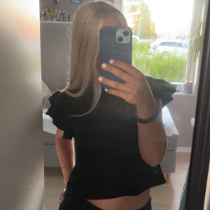 Svart volangärmad topp från ZARA - Svart topp från ZARA i storlek S med korta ärmar och snygga volangdetaljer på axlarna. Rund halsringning och rak passform. Tillverkad i mjuk bomull som känns skön mot huden. Perfekt för dig som vill ha en basic topp med lite extra edge. Säljer eftersom att toppen inte kommer till användning.