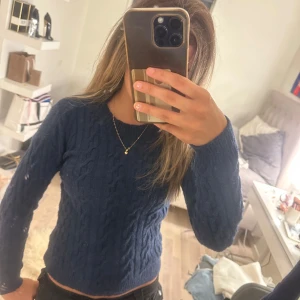Mörkblå stickad tröja med kabelmönster - Säljer en mörkblå stickad tröja med snyggt kabelmönster. Tröjan har rund hals och långa ärmar, perfekt för att hålla sig varm och ändå se chill ut. Passar dig som gillar klassisk stil med en twist. Fråga gärna om du vill veta mer!