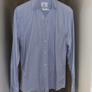 Ljusblå skjorta från Bläck - Ljusblå skjorta från Bläck i storlek S regular fit. Skjortan har ett stilrent och diskret mönster, snygg själv eller under en kavaj. Använd 1 gång och är i superfint skick. Passar dig som är 180-183cm. Hör av dig vid frågor!