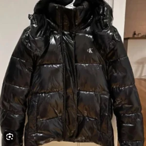 Svart glansig pufferjacka från Calvin Klein - Jättesnygg svart dunjacka från Calvin Klein, kontakta vid fler bilder. Pris kan diskuteras!
