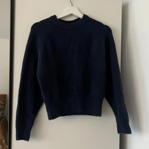 Mörkblå stickad tröja med rund hals från zara - En enkel och stilren mörkblå stickad tröja med rund halsringning och långa ärmar. Tröjan har ribbade muddar vid ärmslut och nederkant, vilket ger en snygg passform. Perfekt att slänga på sig när det är kyligt ute.