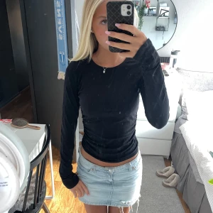 Svart långärmad topp i bomull - Säljer en svart långärmad topp med rund hals. Modellen är slim och sitter snyggt mot kroppen. Materialet är mjukt och stretchigt bomull, perfekt att matcha med jeans eller kjol. Enkel och stilren design utan detaljer eller mönster.