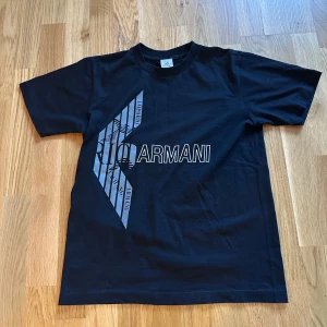 Svart grå t shirt med texten armani på baksidan och framsidan - I en underbar skick använt några gånger men ändå som ny skick kan gå ner i pris vid snabb affär 