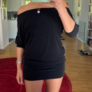 Svart offshoulder kortklänning - Supersnygg svart kortklänning med offshoulder och trekvartsärm. Klänningen har en tight passform nertill och lösare upptill