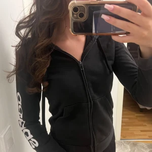 Svart Adidas hoodie med dragkedja - Svart hoodie från Adidas med vit logga längs ena ärmen. Storlek Xs-S pris 75 Kr 🤍🫶