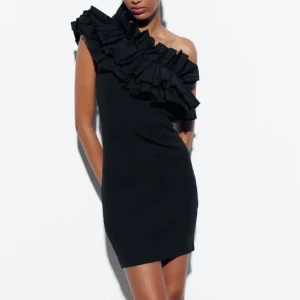 Svart one shoulder klänning Zara - Supersnygg svart kortklänning från Zara med one shoulder och stora volangdetaljer över axeln. Oanvänd, prislapp kvar!