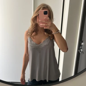 Grå pyjamastopp - Säljer en ljusgrå pyjamastopp från Amisu men köpt på New Yorker med fin spetsdetalj längs v-ringningen och axelbanden. Toppen är ärmlös, i storlek L men passar även M💕💕