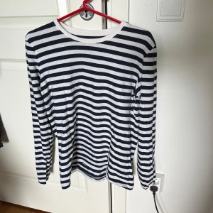 Randig långärmad tröja i bomull - Långärmad tröja med marinblå och vita ränder. 