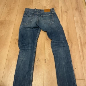Replay Grover straight fit jeans blå - Säljer ett par Replay Grover jeans i klassisk blå tvätt med slitningar och raka ben. Jeansen har fem fickor, snygga detaljer och straight fit. Perfekta för dig som gillar en avslappnad men ändå stilren look. Strl 30/32