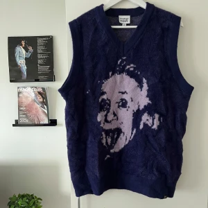 Lila stickad väst från Vintage Supply - Mjuk och fluffig lila stickad väst från Vintage Supply med v-ringning och ett stort motiv framtill. Västen har breda ärmöppningar och en relaxed passform, perfekt att styla över en t-shirt eller skjorta för en cool look.