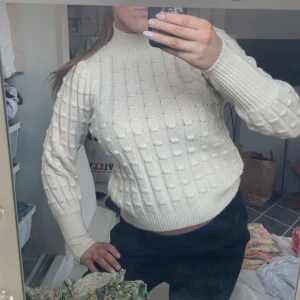 Vit stickad tröja från Vero Moda - Säljer en krämvit stickad tröja från Vero Moda i storlek XS. Tröjan har hög hals, ribbade muddar och ett snyggt rutigt stickat mönster. Perfekt för lager-på-lager och passar till både jeans och kjol.