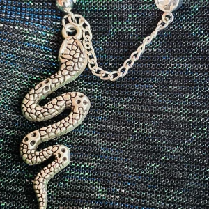 By prisförslag- 1 st Silvrigt dubbel örhänge med orm och kedja - Coolt dubbelt örhänge i silverfärgad metall med en detaljerad orm som hänger i en kedja. Ormen har ett realistiskt mönster och örhänget är dekorerat med en glittrig sten upptill. Perfekt för dig som vill sticka ut med din stil.