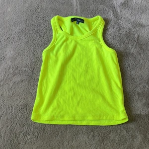 Neongul ribbad linnetopp XOXO Friends - Säljer en riktigt snygg neongul ribbad linnetopp från XOXO Friends. Toppen är ärmlös med klassisk racerback och har en tajt passform som sitter perfekt. Perfekt för dig som vill sticka ut och addera färg till din outfit!
