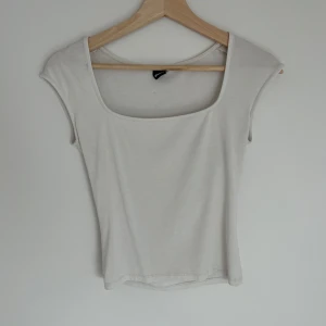 Vit linnetopp från Gina Tricot - En vit linnetopp från Gina Tricot med fyrkantig urringning och ärmlös design. Perfekt att matcha med jeans eller kjol för en clean look.
