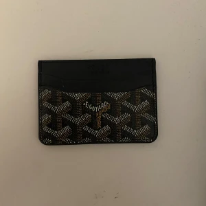 Plånbok  - Slimmad och stilren plånbok från H&M med mönster i svart, brunt och vitt. Perfekt för kort och sedlar, med flera fack och klassisk logga framtill. Gjord i skinn med lyxig känsla och snygg design som sticker ut.