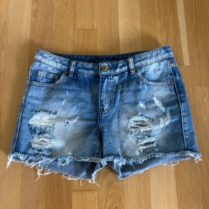 Slitna jeansshorts  - Så snygga lågmidjade jeansshorts med blekt tvätt och slitningar. Köpta secondhand, knappt använda så i toppskick. Strl på lappen är L.