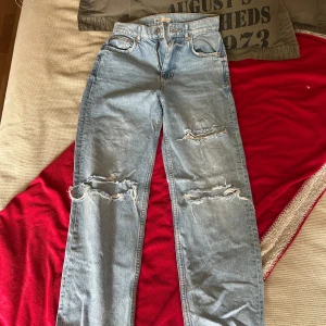 Ljusblå ripped jeans från g perfect jeans - Säljer ett par ljusblå jeans från g perfect jeans i storlek 34. De har raka ben, klassisk femficksmodell och flera slitningar och hål på framsidan för en riktigt trendig, avslappnad look. Jag kan tyvärr inte ha dessa jeans längre men jag hoppas att någon annnan skulle vilja bära dom här jeansen