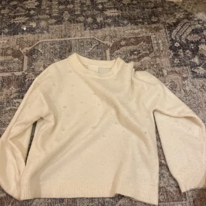 Vit pärlstickad tröja från H&M XS - Säljer en superfin vit stickad tröja från H&M i storlek XS. Tröjan har pärldetaljer på framsidan och ärmarna, vilket ger en extra touch. Den har rund hals och långa ärmar, perfekt för att lyfta din outfit med lite bling.