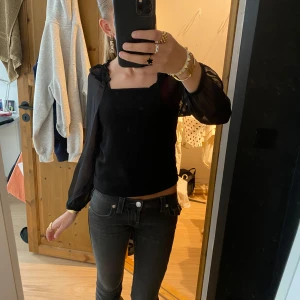 Svart blus  - Hej!! Jag säljer en så så fin svart blus med transparenta, långa ärmar och fyrkantig ringning. Toppen kan bäras både offshoulder och med axelband. Ärmarna är i tunnare material och har resår vid handlederna. Säljer då den blivit lite för liten och har ingen användning av den, annars tycker jag den är super fin!! 