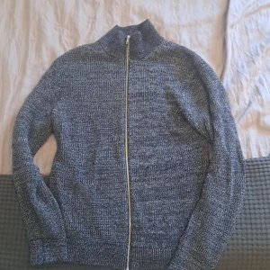 Mörkgrå stickad kofta från East West - Säljer en mörkgrå stickad kofta från East West i storlek S. Koftan har en snygg ribbad struktur, hög krage och hel dragkedja framtill. Materialet är mjukt och passar perfekt när du vill ha något bekvämt och stilrent. Hör av dig i pm vid intresse. Köpt för cirka 6 månader sen. Knappt använd